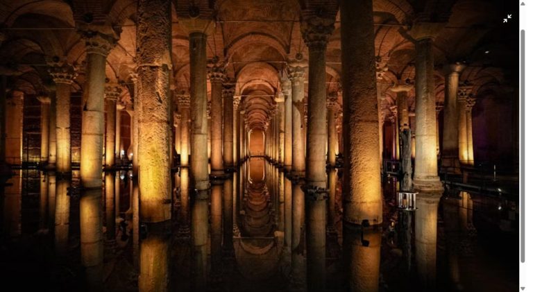 Golden-lit columns reflected in the still water of a historic underground cistern